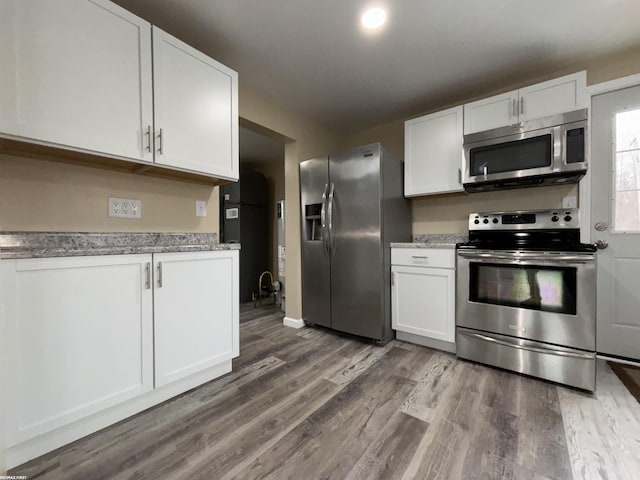 kitchen featuring light stone countertops, appliances with stainless steel finishes, hardwood / wood-style floors, and white cabinets