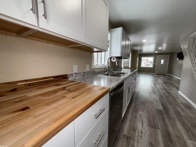 kitchen featuring butcher block counters, sink, dark hardwood / wood-style floors, black dishwasher, and white cabinets