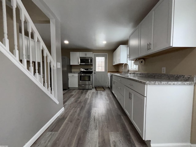 kitchen with stainless steel appliances, sink, dark wood-type flooring, and white cabinets