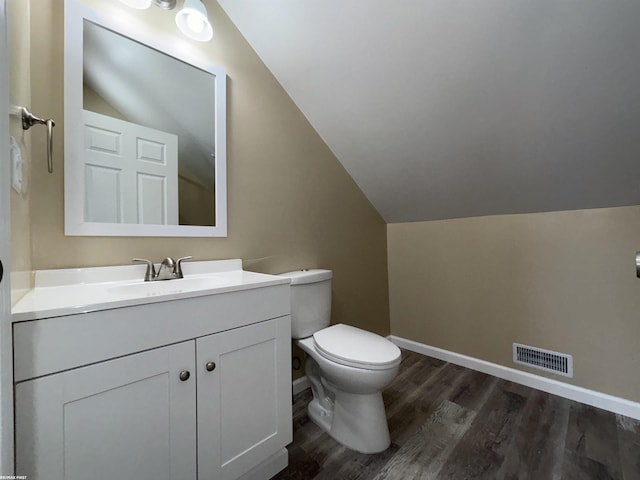 bathroom with vanity, wood-type flooring, toilet, and vaulted ceiling