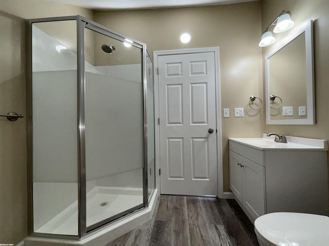bathroom featuring wood-type flooring, toilet, an enclosed shower, and vanity