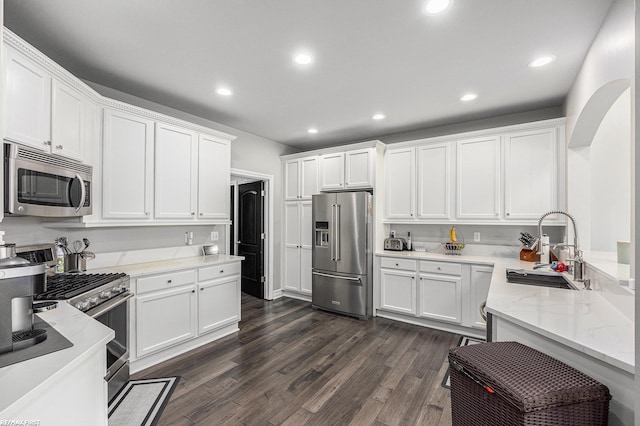 kitchen featuring appliances with stainless steel finishes, sink, white cabinets, dark hardwood / wood-style flooring, and light stone countertops