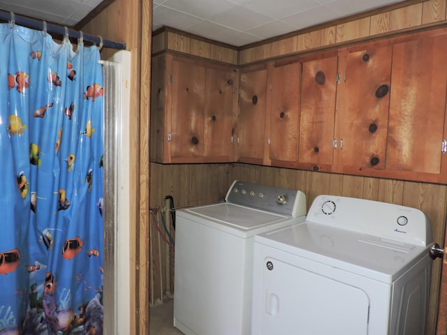 laundry room featuring wooden walls and washer and dryer