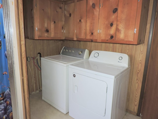 clothes washing area featuring washer and clothes dryer and cabinets