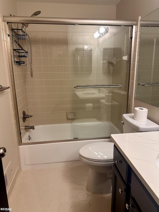 full bathroom featuring vanity, tile patterned flooring, bath / shower combo with glass door, and toilet