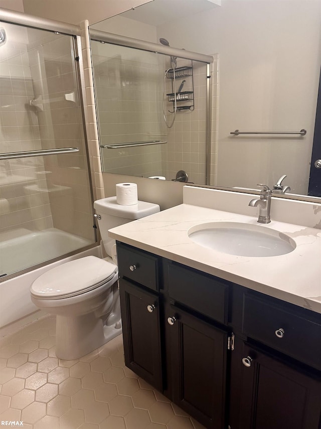 full bathroom with tile patterned flooring, vanity, combined bath / shower with glass door, and toilet