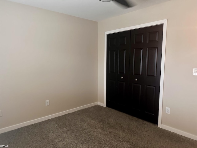 unfurnished bedroom featuring dark carpet and a closet