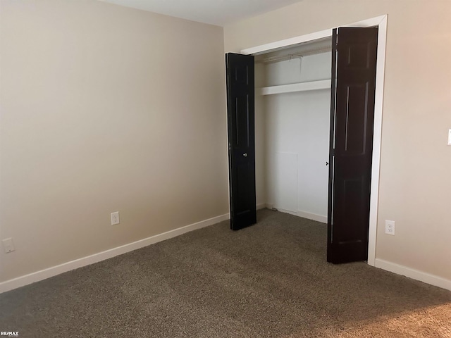 unfurnished bedroom with dark carpet and a closet