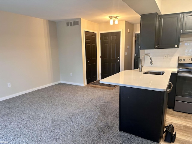 kitchen with decorative backsplash, kitchen peninsula, sink, and stainless steel electric range