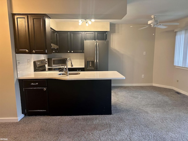 kitchen featuring sink, appliances with stainless steel finishes, backsplash, carpet flooring, and kitchen peninsula