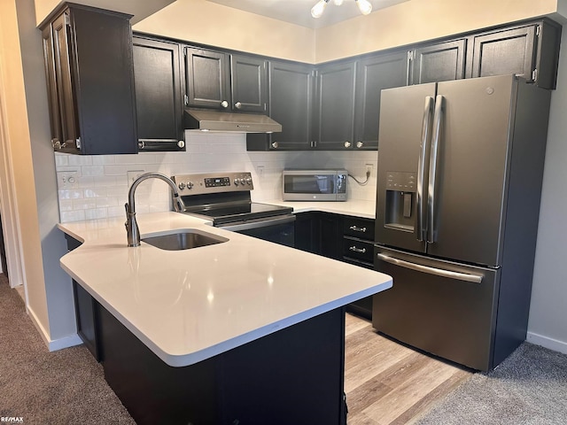 kitchen with appliances with stainless steel finishes, sink, a kitchen breakfast bar, decorative backsplash, and kitchen peninsula