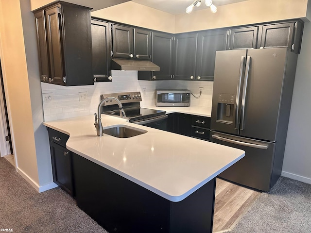 kitchen with tasteful backsplash, sink, kitchen peninsula, and appliances with stainless steel finishes