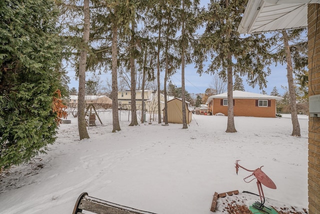 yard layered in snow featuring a storage shed