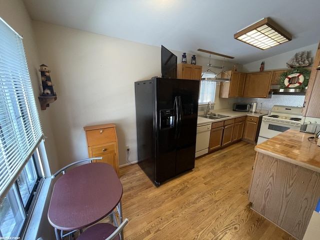 kitchen featuring sink, light wood-type flooring, wooden counters, hanging light fixtures, and white appliances