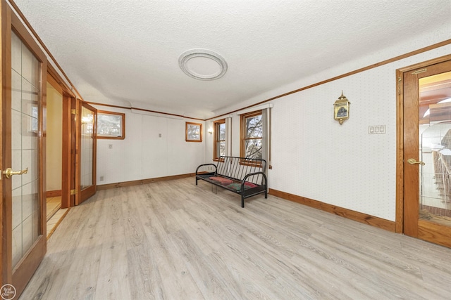 unfurnished room with a textured ceiling, light hardwood / wood-style floors, and french doors