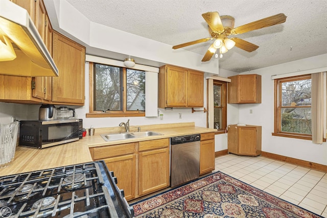 kitchen with range with gas cooktop, dishwasher, sink, light tile patterned floors, and a textured ceiling