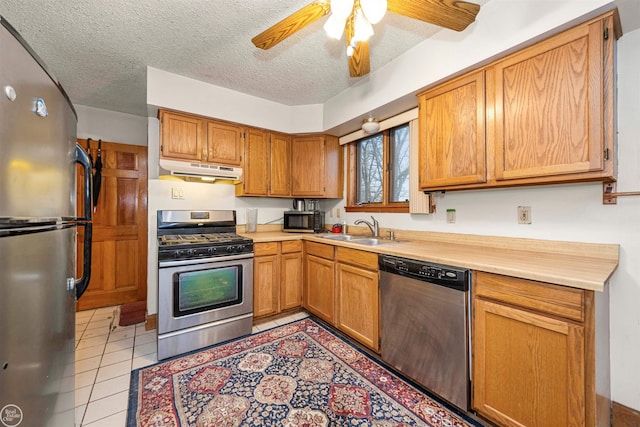 kitchen featuring sink, a textured ceiling, light tile patterned floors, ceiling fan, and stainless steel appliances