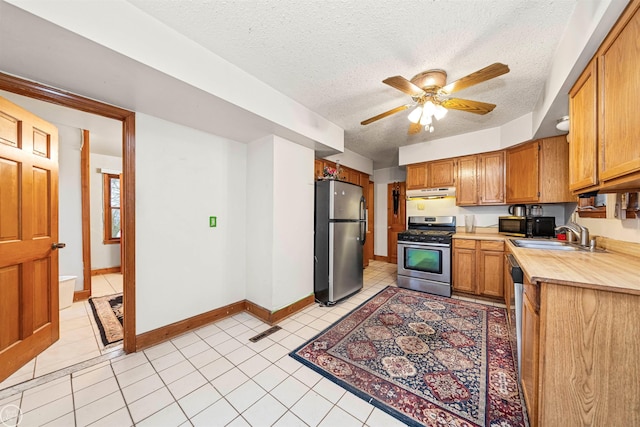 kitchen featuring sink, stainless steel appliances, a textured ceiling, and ceiling fan