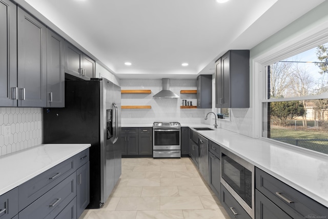 kitchen featuring sink, tasteful backsplash, gray cabinets, stainless steel appliances, and wall chimney range hood