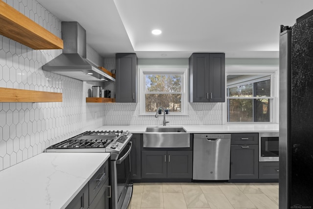 kitchen with ventilation hood, sink, decorative backsplash, light stone counters, and stainless steel appliances