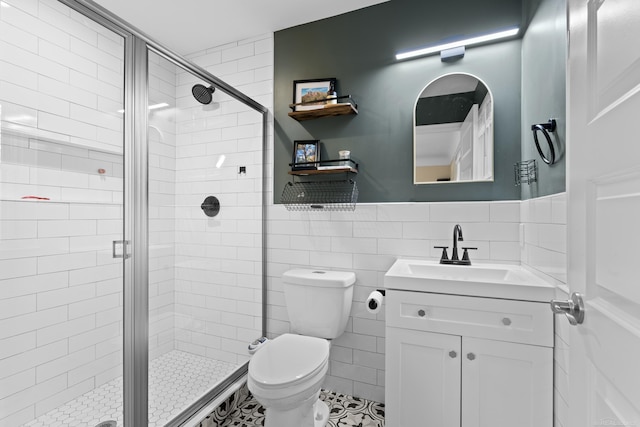 bathroom featuring tile walls, vanity, a shower with door, and toilet