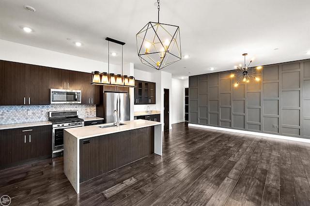 kitchen with pendant lighting, stainless steel appliances, a chandelier, and a kitchen island with sink