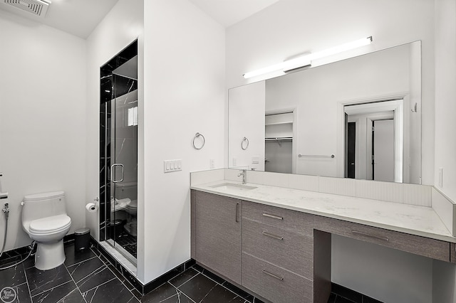 bathroom featuring vanity, a shower with shower door, and toilet