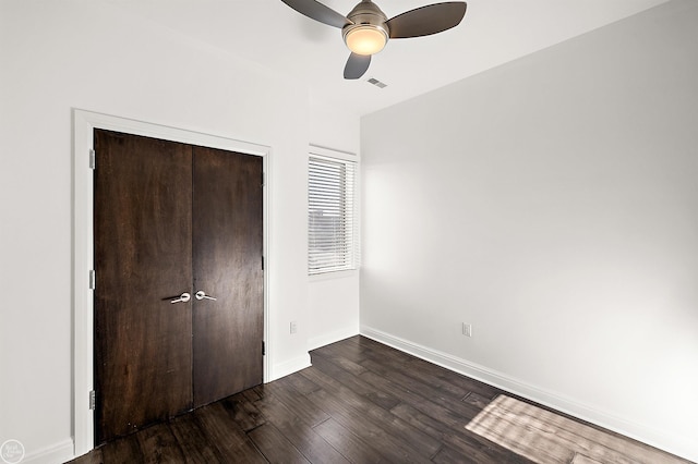 unfurnished bedroom featuring dark wood-type flooring, ceiling fan, and a closet