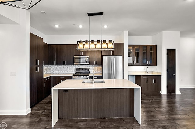 kitchen featuring appliances with stainless steel finishes, a kitchen island with sink, sink, and hanging light fixtures