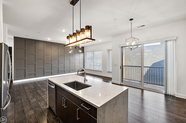 kitchen featuring sink, a kitchen island with sink, stainless steel appliances, dark hardwood / wood-style floors, and decorative light fixtures