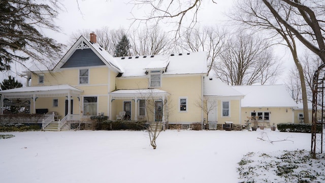 snow covered house featuring a porch