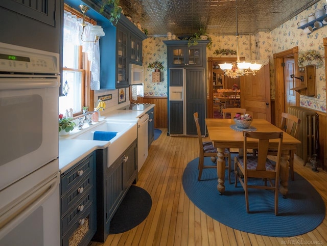 kitchen with decorative light fixtures, radiator heating unit, light hardwood / wood-style floors, and a chandelier