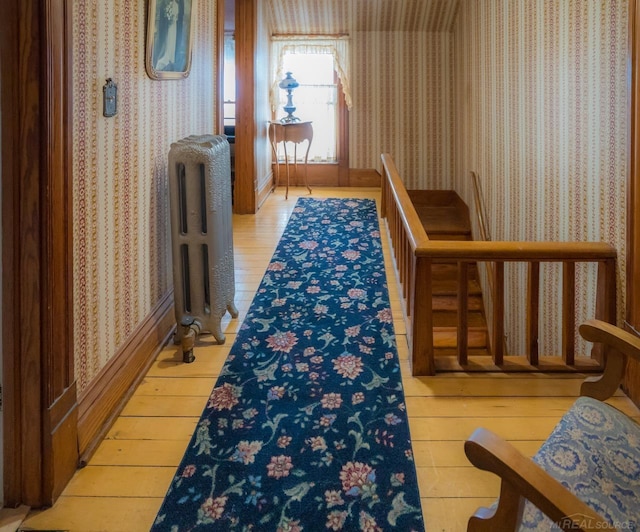 corridor featuring radiator heating unit and light hardwood / wood-style flooring