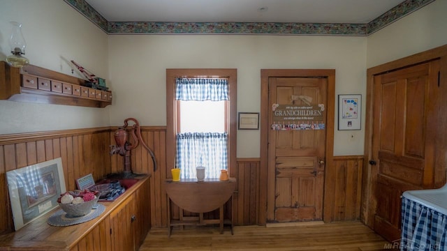 foyer with light wood-type flooring and wood walls