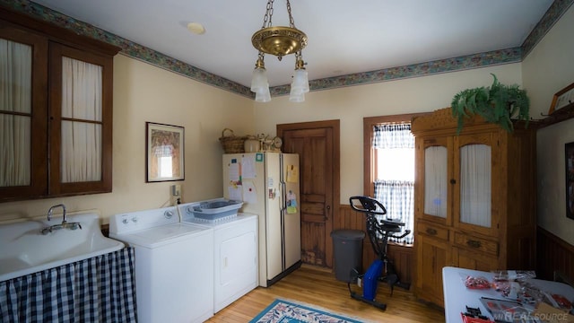 clothes washing area with separate washer and dryer, sink, and light wood-type flooring