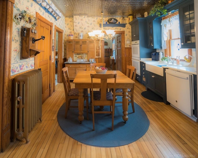 dining room featuring radiator, a notable chandelier, light hardwood / wood-style flooring, and sink