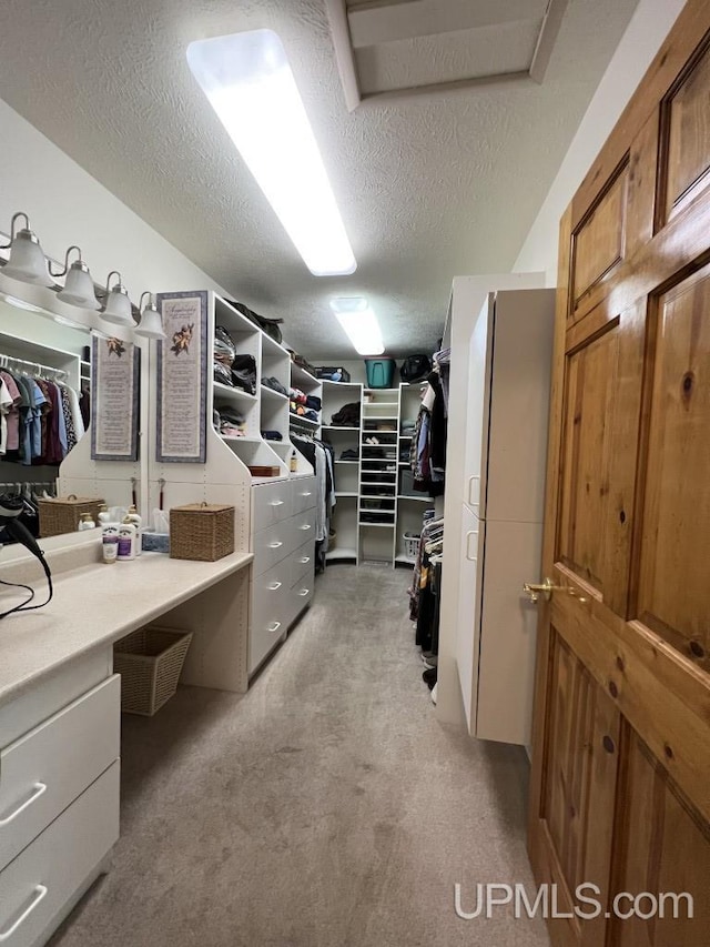 walk in closet with light colored carpet
