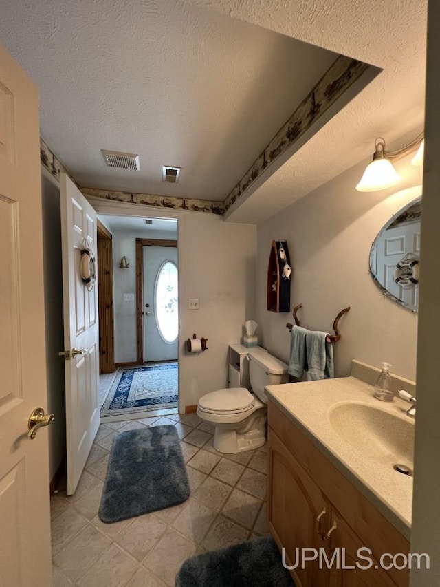 bathroom with vanity, toilet, and a textured ceiling