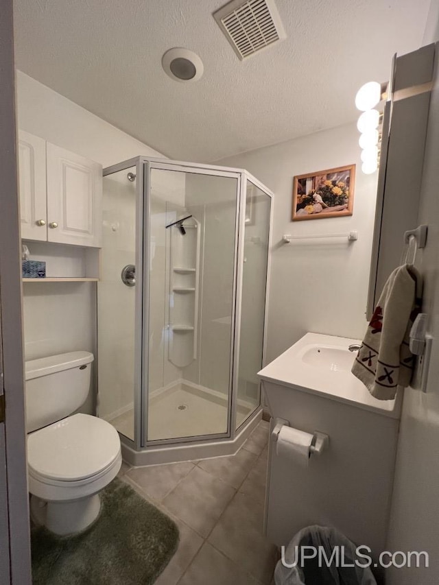 bathroom with toilet, tile patterned flooring, a shower with door, and a textured ceiling