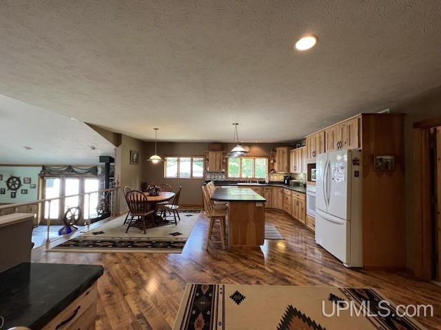 kitchen with pendant lighting, white appliances, dark wood-type flooring, and a kitchen breakfast bar