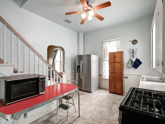 kitchen featuring sink, ceiling fan, white cabinetry, stainless steel refrigerator with ice dispenser, and gas stove