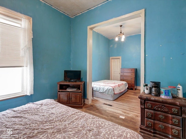 bedroom with an inviting chandelier and light wood-type flooring