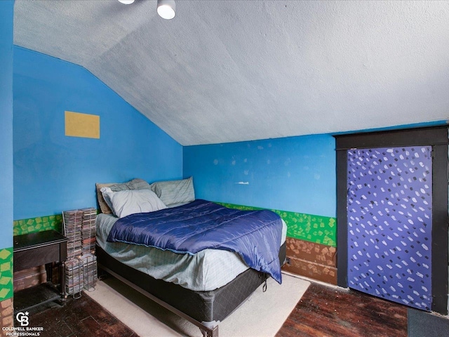 bedroom with wood-type flooring, vaulted ceiling, and a textured ceiling