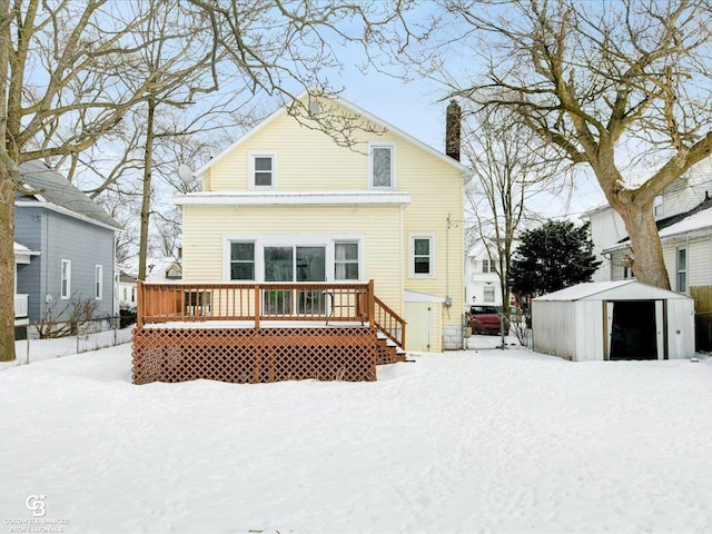 snow covered property with a shed and a wooden deck