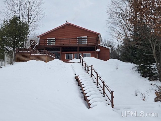 snow covered house featuring a deck