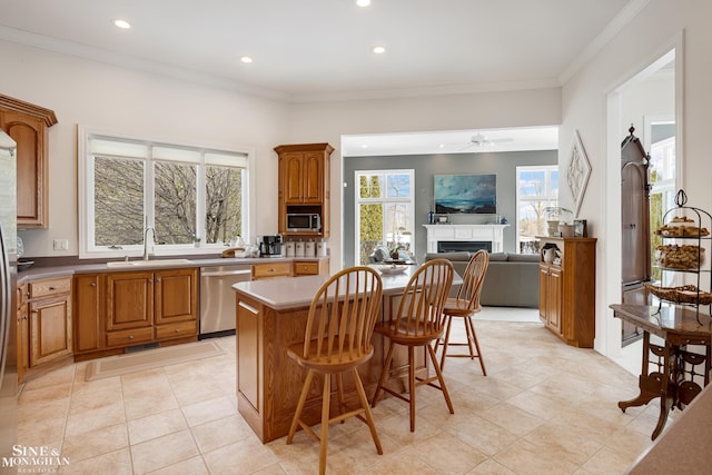 kitchen featuring a kitchen island, a breakfast bar, sink, stainless steel appliances, and crown molding