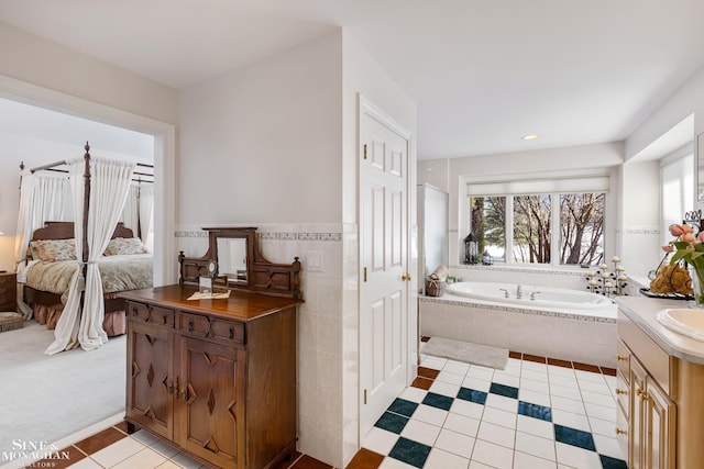 bathroom with tiled tub, vanity, and tile patterned floors