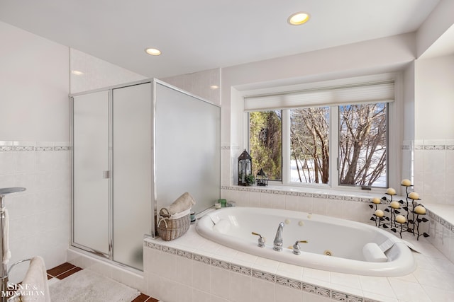 bathroom with shower with separate bathtub and tile walls