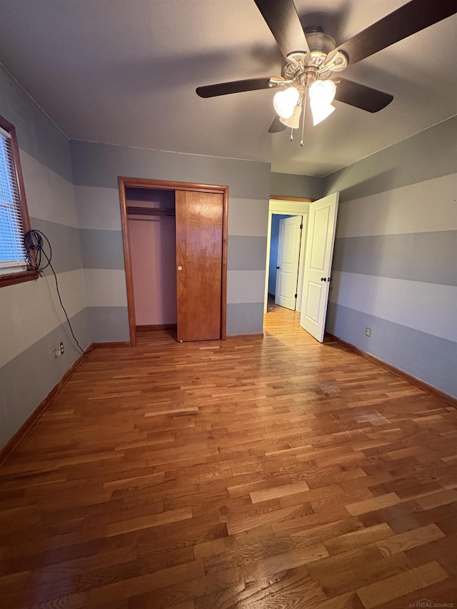 unfurnished bedroom featuring hardwood / wood-style floors, ceiling fan, and a closet