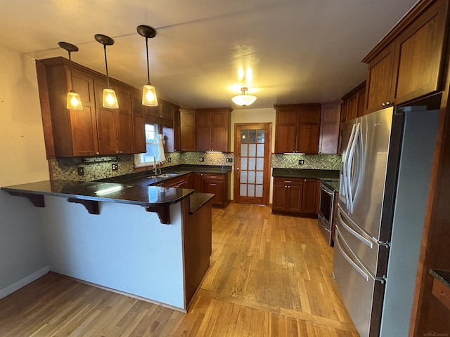 kitchen with appliances with stainless steel finishes, decorative light fixtures, kitchen peninsula, and a kitchen bar